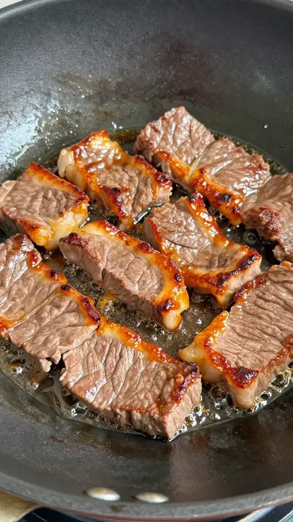 closeup of beef slices sizzling in wok with caramelized edges