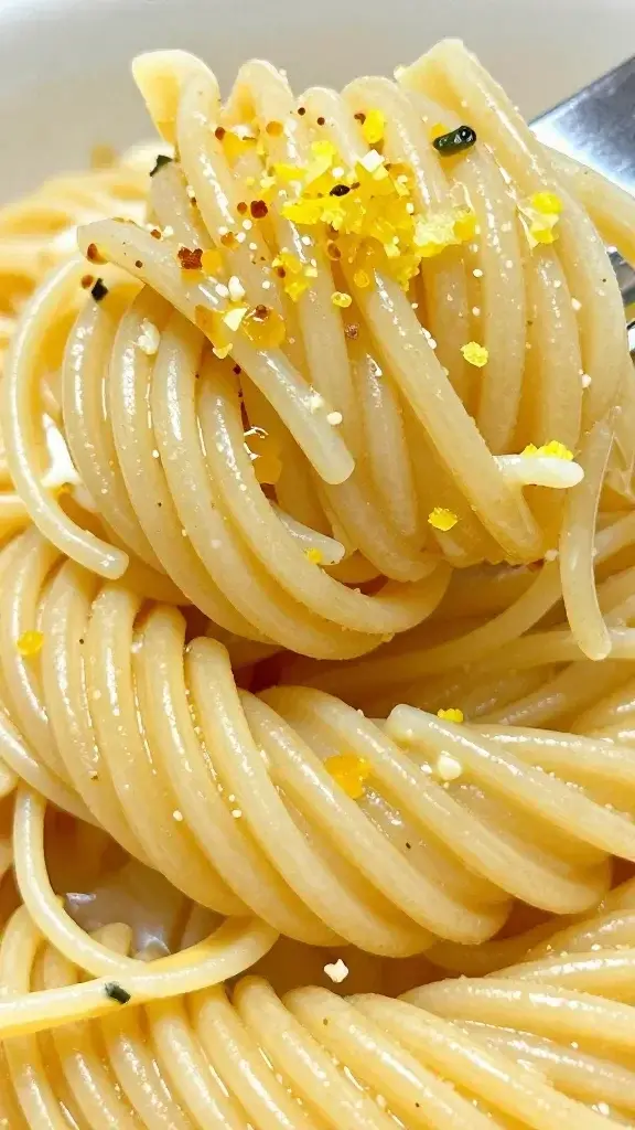 Closeup angel hair pasta twirl with garlic butter, lemon zest top